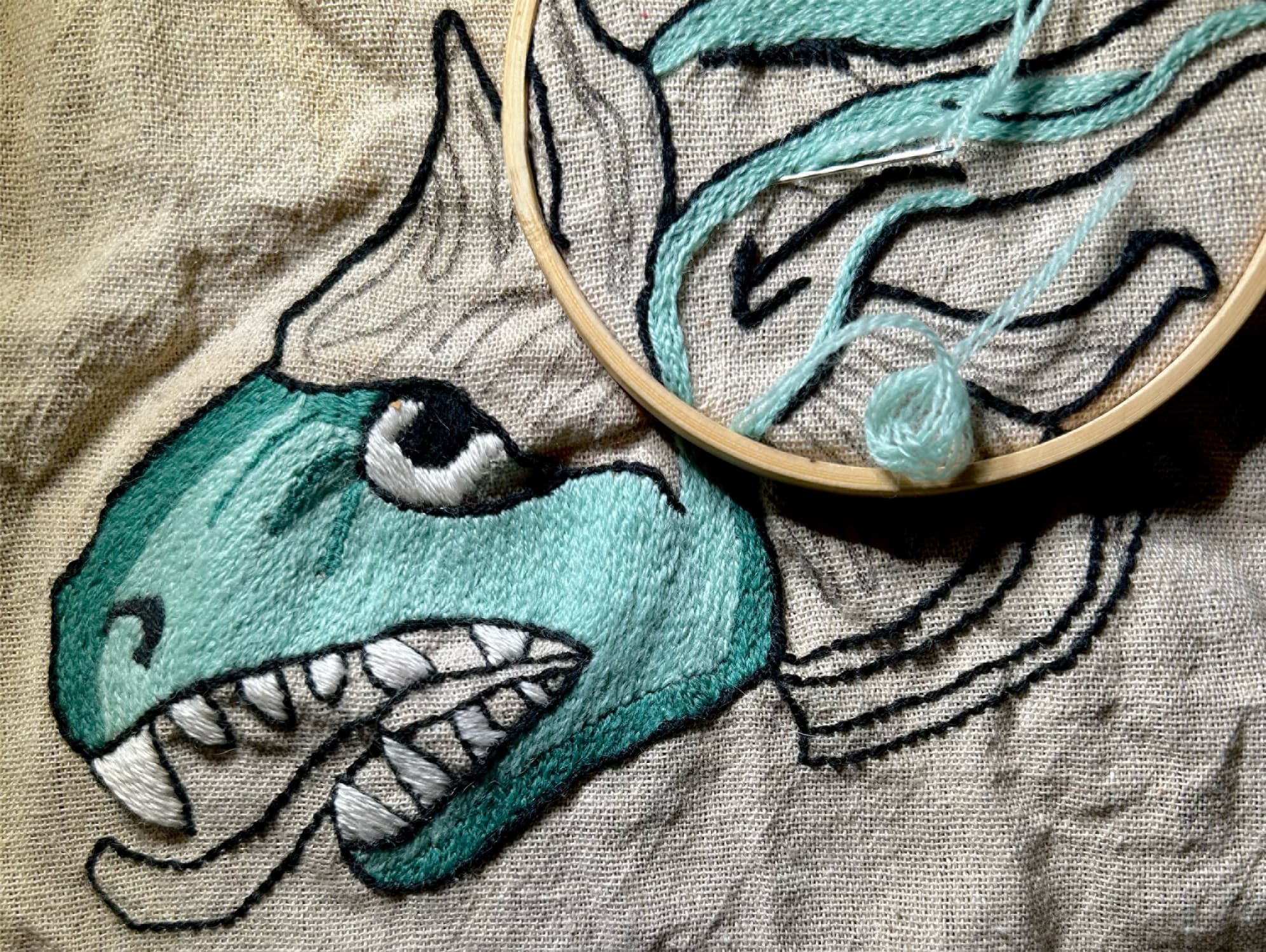 A profile of a medieval beast stitched onto an embroidery hoop