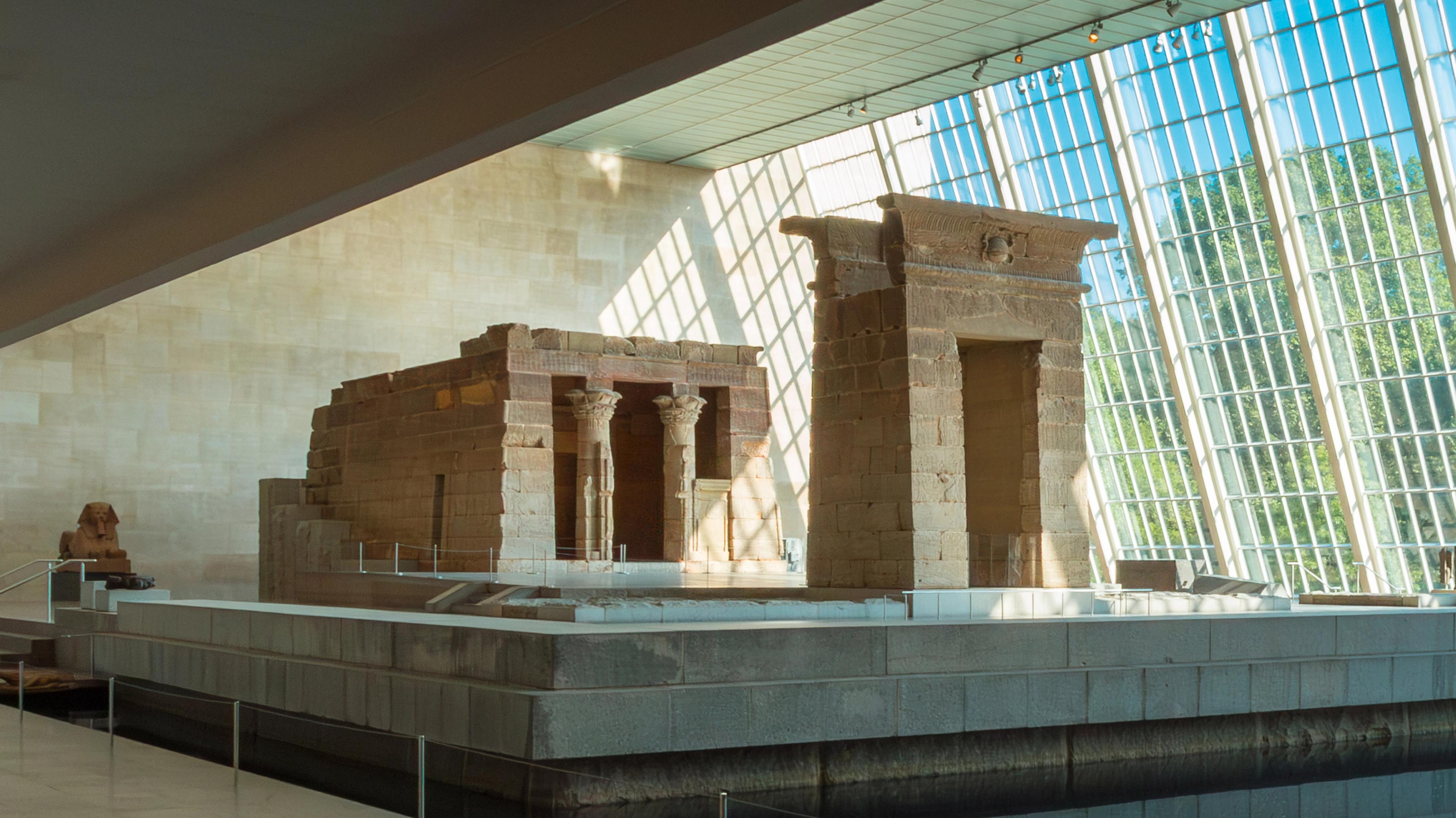 An ancient Egyptian temple structure with two columns in front displayed inside a museum.  