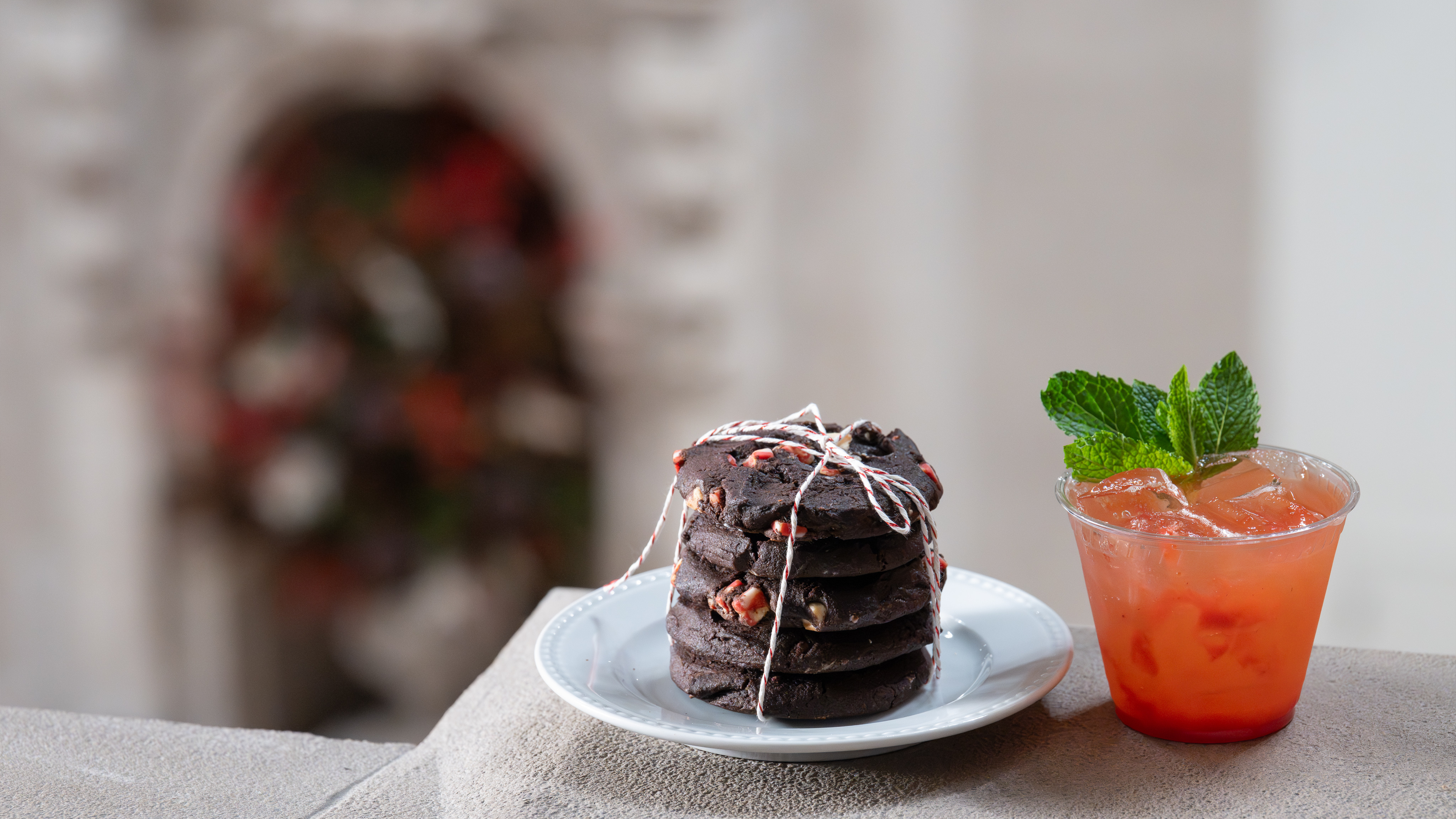 A stack of holiday cookies wrapped in ribbon next to a cocktail. 